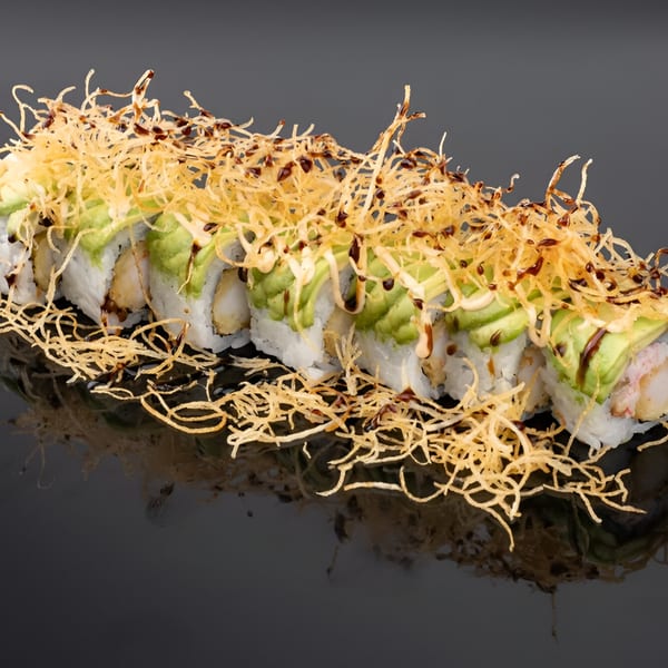 YuGo Sushi & More's sushi roll with avocado, crispy fried onions, and dark sauce on a black surface.